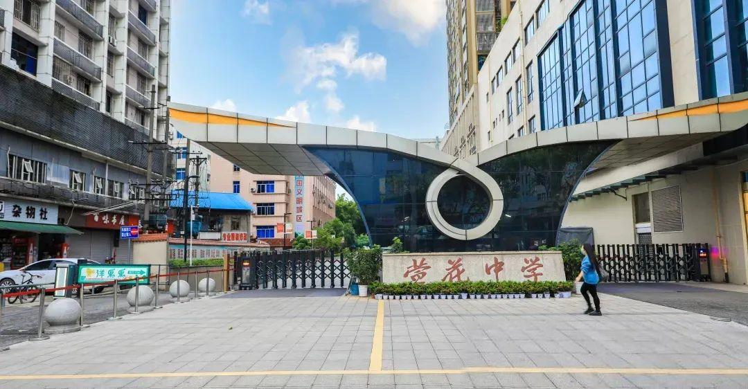学校大门原貌全景，两侧楼房、商铺和道路均保留